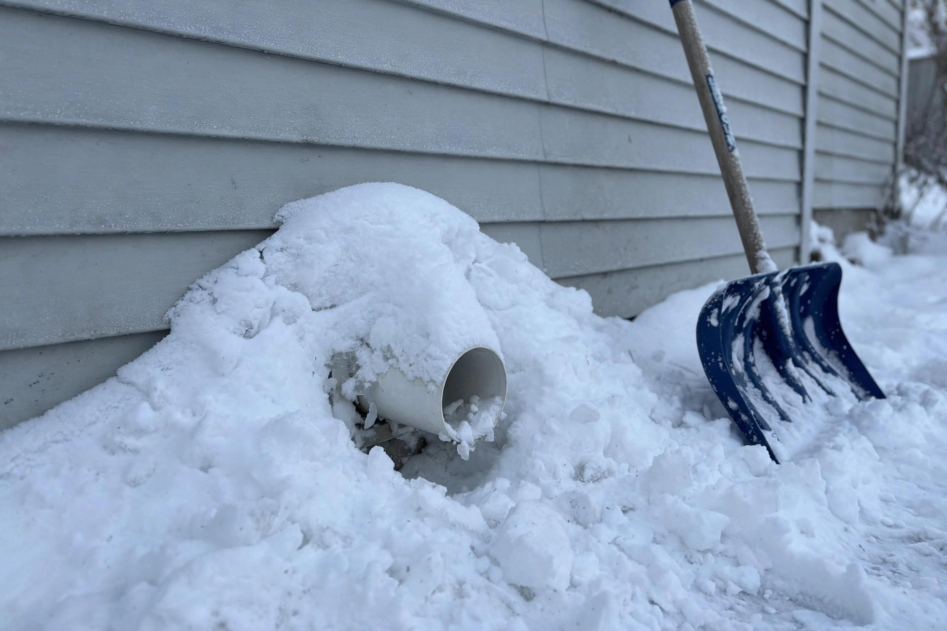 Ice and frost around a furnace vent pipe on an outside wall